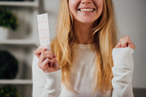 cropped view of woman showing winner gesture while holding lottery ticket